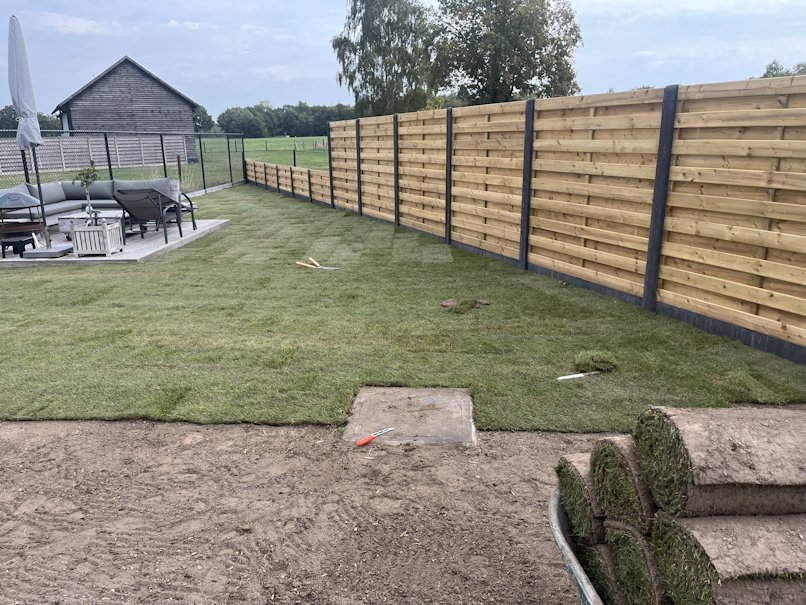 Nieuw gelegd gazon met schutting en loungeterras