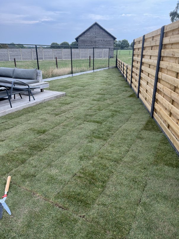 Vers gelegde grasplaten langs een houten afsluiting
